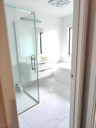 a bathroom with a glass shower and a white tile floor at peaceful gully view home -4 bedrooms in Hamilton