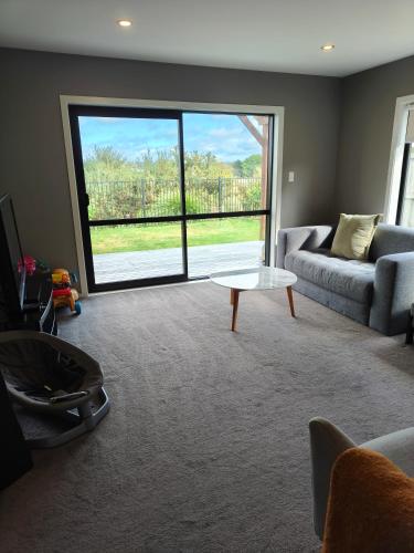 a living room with a couch and a table at peaceful gully view home -4 bedrooms in Hamilton