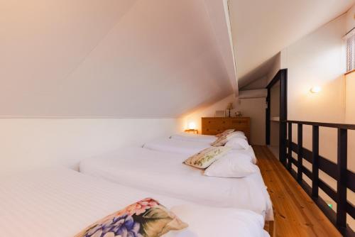 a row of white beds in a room at 4月リニューアルOpen! 全室エアコン完備! Cottage あかいやねｰ The Red Roof Cottage YamanakaKoｰ in Yamanakako