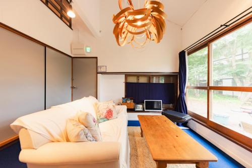 a living room with a couch and a table at 4月リニューアルOpen! 全室エアコン完備! Cottage あかいやねｰ The Red Roof Cottage YamanakaKoｰ in Yamanakako
