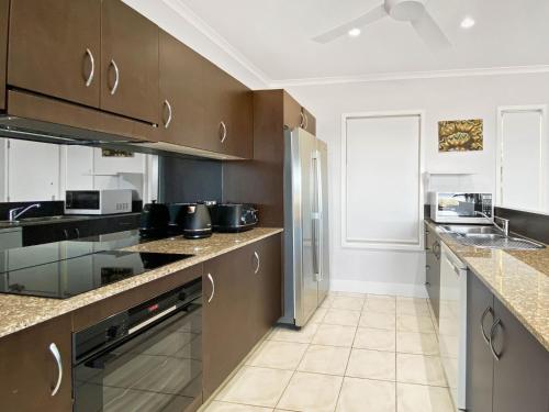 a large kitchen with brown cabinets and appliances at Magnetic Docks Townhouse 5 in Nelly Bay