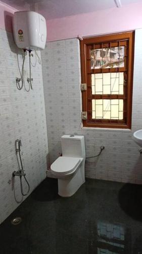 a bathroom with a toilet and a window and a sink at Heritage House Shillong in Shillong