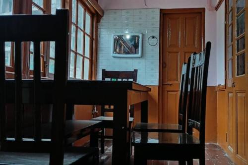 a dining room with a wooden table and chairs at Heritage House Shillong in Shillong