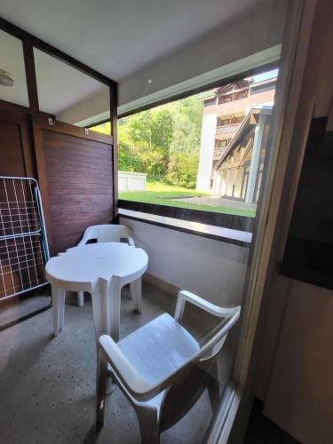 un balcon avec une table, des chaises et une fenêtre dans l'établissement Appartement cosy proche centre thermal et télécabine 3 vallées, à Brides-les-Bains