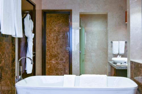 a bathroom with a bath tub and a sink at Grand Millennium Tabuk in Tabuk