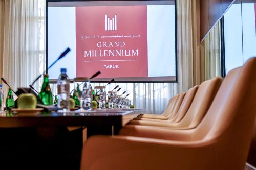 a dining room with a table and chairs and a large screen at Grand Millennium Tabuk in Tabuk