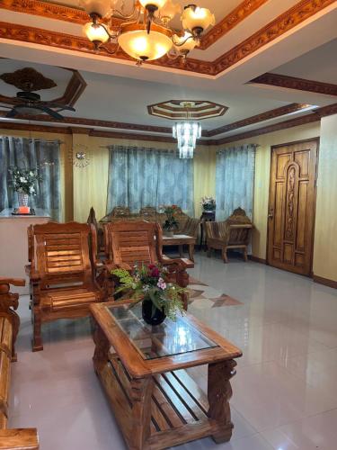 a living room with wooden chairs and a couch at Lovely Bedroom in Lila, Bohol with WIFI, AC and Ref in Lila