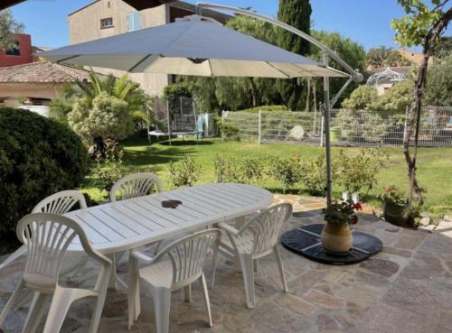 une table et des chaises blanches avec un parasol dans l'établissement Appartement 4 pers avec terrasse et piscine, à Bormes-les-Mimosas