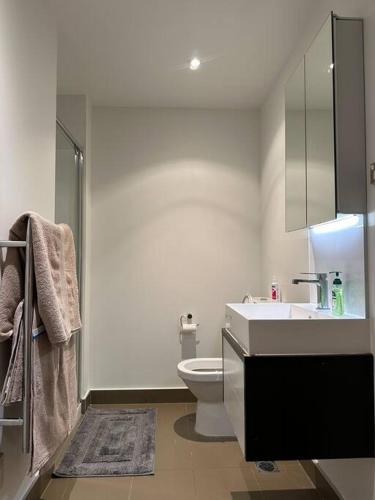 a white bathroom with a sink and a toilet at City Apartment with SKY Tower view in Auckland
