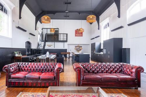 a living room with two leather couches in a room at The Great Hall, Edwinstowe Hall in Edwinstowe