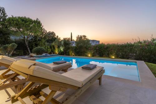 a swimming pool with lounge chairs next to a swimming pool at LDV ZANTE VILLAS - Luxury Dream Villa in Pandokrátor
