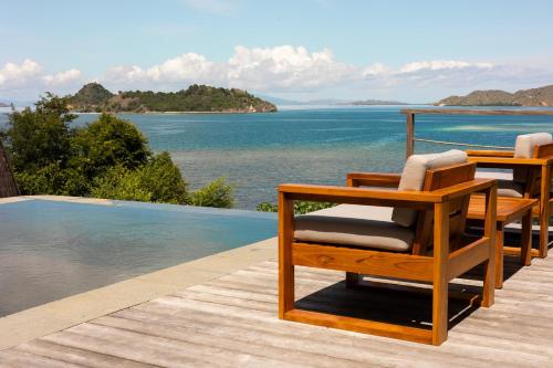 two chairs sitting on a deck next to a swimming pool at Menjaga Bay in Labuan Bajo