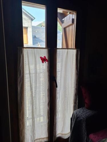 two windows with white curtains with a red bow at Apartamento Amatista en Broto in Broto