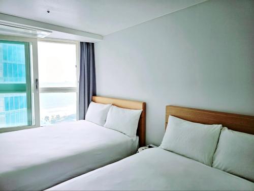 two beds in a hotel room with a window at Ciel de Mer in Busan