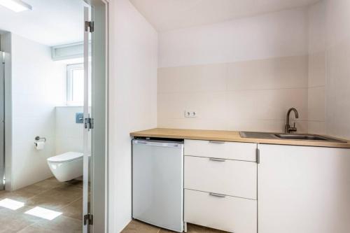 a white kitchen with a sink and a toilet at Casa Cinco Cupulas in Armação de Pêra