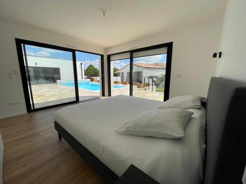 a bedroom with a large bed and large windows at Magnifique Villa Familiale de 200m2 4 Chambres et un Sauna in Saint-Sauveur-dʼAunis