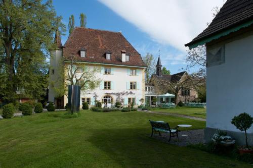 una gran casa blanca con un banco en el patio en Schloss Ueberstorf - Tafeln, Tagen, Träumen en Ueberstorf