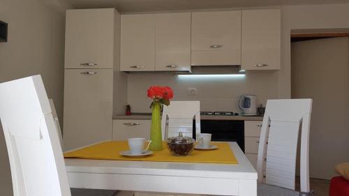 a kitchen with a table with a vase of flowers on it at Apartmani Irena in Rtina