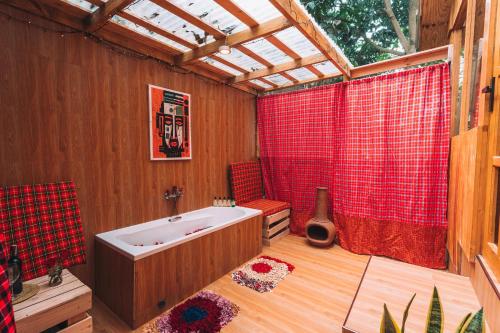 a bathroom with a tub and a red shower curtain at Banana Farm Eco Hostel in Arusha