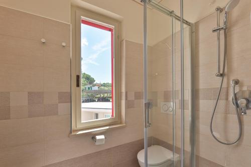 a bathroom with a shower and a toilet and a window at Camping Village Le Calanchiole in Capoliveri