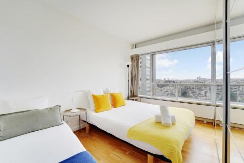 une chambre avec deux lits et une grande fenêtre dans l'établissement Seine & Eiffel 100m2 avec vue panoramique parking, à Paris