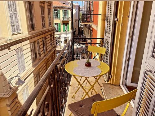 une table et des chaises jaunes sur un balcon dans l'établissement Masséna street, 2 rooms balcony, à Nice