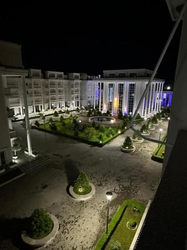 a night view of a large building with trees in a courtyard at Apartament REJ VELIPOJE in Shkodër