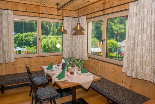 a dining room with a table and chairs and windows at Hotel Oberwirt - nahe an Saalbach und Zell am See, Viehhofen Sommercard in Viehhofen