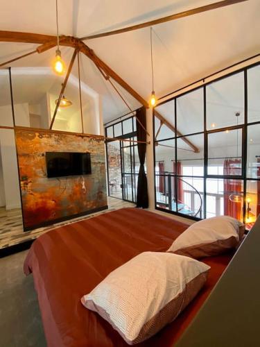 - une chambre avec un grand lit dans une pièce dotée de fenêtres dans l'établissement Appartement Loft neuf plein cœur de Royan, à Royan