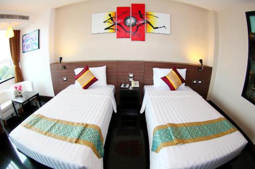 a hotel room with two beds and a table at Arthitaya Green Nature Hotel & Lakkhana Poolside Resort in Pattaya North