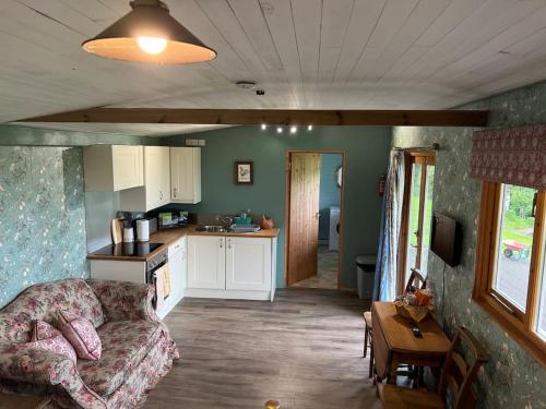 a living room with a couch and a kitchen at Country garden lodge on Devon Cornwall border in Lifton