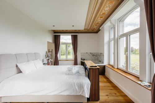 a bedroom with a large white bed and windows at Nuit romantique au château de Saint Vitu vue sur le parc 103 in Tinlot