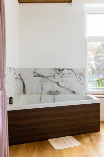 a bath tub in a bathroom with a marble wall at Nuit romantique au château de Saint Vitu vue sur le parc 103 in Tinlot