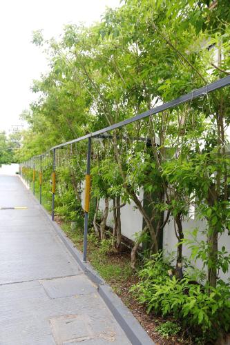 a fence next to a sidewalk next to trees at Arthitaya Green Nature Hotel & Lakkhana Poolside Resort in Pattaya North
