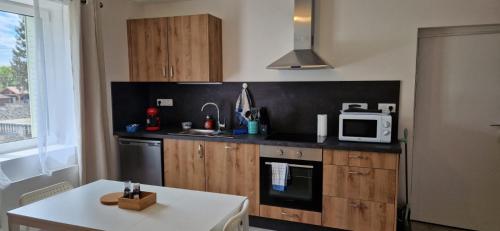 - une cuisine avec des placards en bois et une table blanche dans l'établissement A 2 pas de la BASILIQUE, à Bourg-en-Bresse