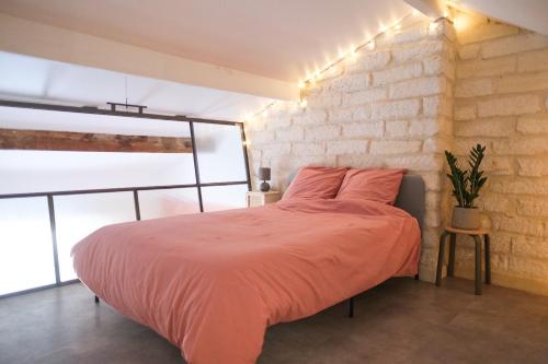 un lit dans une chambre avec un mur de briques dans l'établissement Cosy T3 Style Loft proche Gare St Roch, à Montpellier