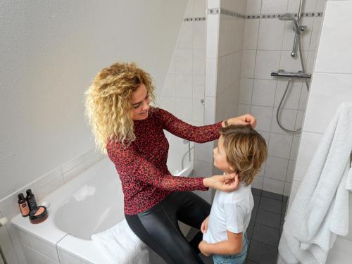 Eine Frau bürstet einem Kind die Haare im Badezimmer in der Unterkunft Tulp en Zee in Noordwijk