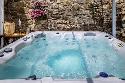 a jacuzzi tub in front of a stone wall at Luxury Limonaia with Jacuzzi near Florence in San Jacopo al Girone