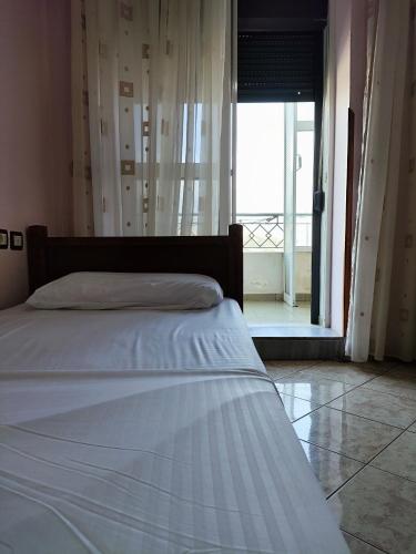 a bed in a room with a large window at Koshi Home in Gjirokastër