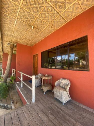 a deck with chairs and a table on a building at Kayla'a Beach Resort And Blackeye Brewing in Dimiao