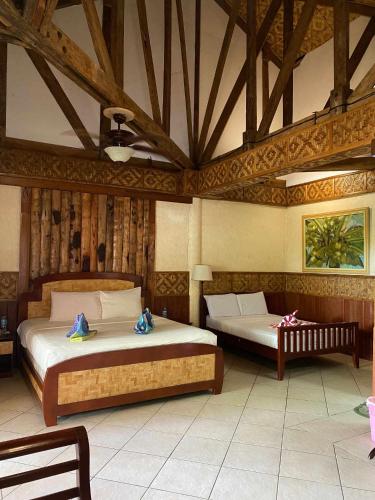 two beds in a room with wooden ceilings at Kayla'a Beach Resort And Blackeye Brewing in Dimiao