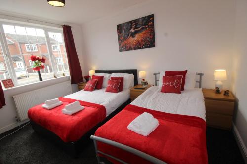 two beds in a hotel room with red pillows at High Street House Thurnscoe by Smart Corporate Stays in Barnsley