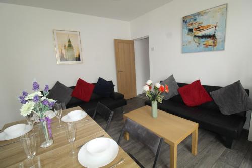 a living room with a couch and a table with flowers at High Street House Thurnscoe by Smart Corporate Stays in Barnsley