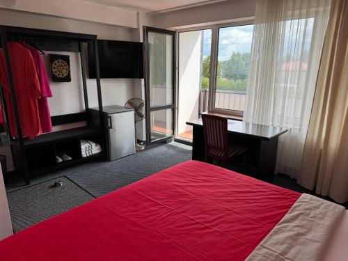 a bedroom with a red bed and a desk and a window at Baskervilu Muiža in Sērenes