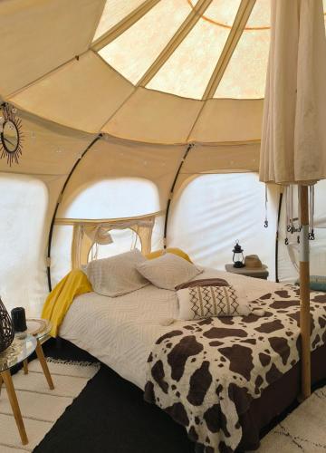 une chambre avec un lit dans une tente dans l'établissement Nuit étoilée en pleine Nature, à Solignac
