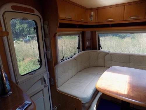 a white couch in an rv with two windows at Caravan du Loch in Gaël