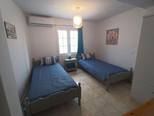une chambre avec deux lits et une fenêtre dans l'établissement Cosy Kotroni, Greek cuteness, townhouse for 6, à Skiathos Chora