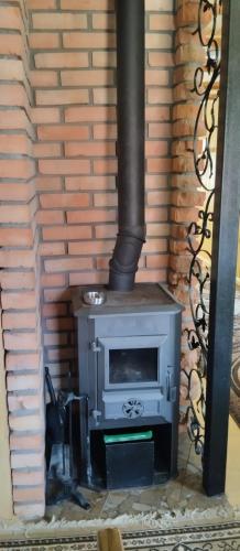 a woodburning stove in a room with a brick wall at Stanica Karpacka 4x4 in Mohnate