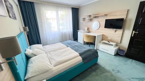a bedroom with a bed and a desk and a television at Complex Turistic Monaco in Baile Felix
