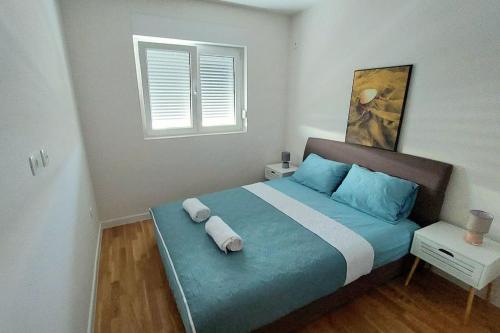 a bedroom with a bed with blue pillows and a window at Urban Escape Apartment in Pobrežje